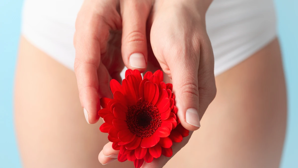Donna in slip bianchi che tiene un fiore rosso, simbolo della salute e dell’estetica intima femminile
