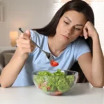 Donna con disturbi alimentari che tenta di mangiare un'insalata.